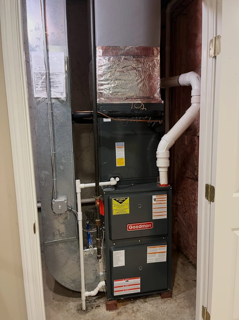 New Goodman furnace installed in a closet with white PVC pipes and foil wrapped ductwork